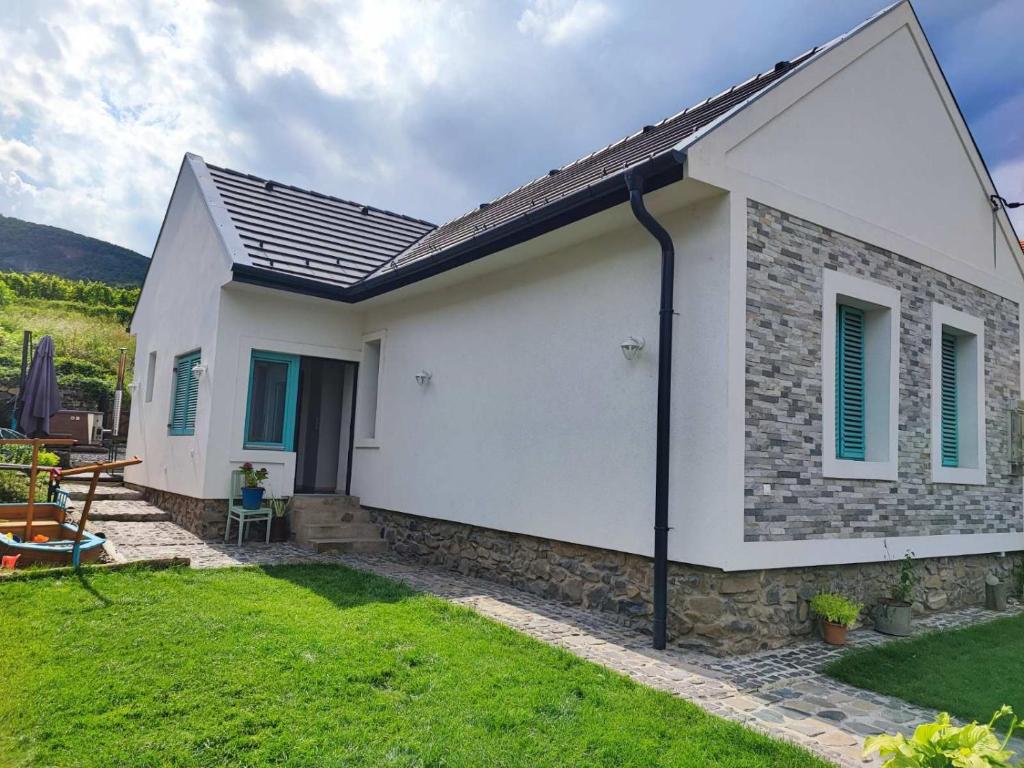 una pequeña casa blanca con un patio de césped en Veled Teljes Vendégház Badacsony, en Badacsonytomaj