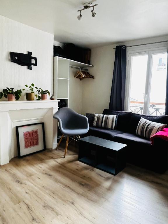- un salon avec un canapé noir et une cheminée dans l'établissement Charmant studio au centre de PARIS, à Paris
