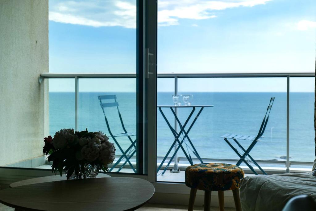 1 dormitorio con vistas al océano, mesa y sillas en Appartement vue imprenable sur la baie des Sables - 4 personnes, en Les Sables-dʼOlonne