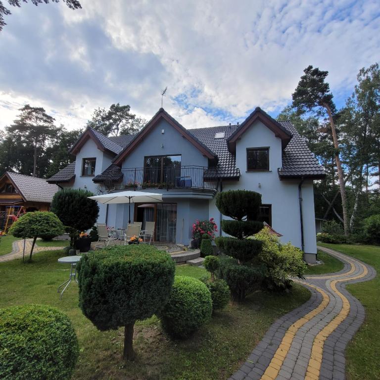 a white house with a walkway in front of it at Pokoje & Domki GABI in Pobierowo