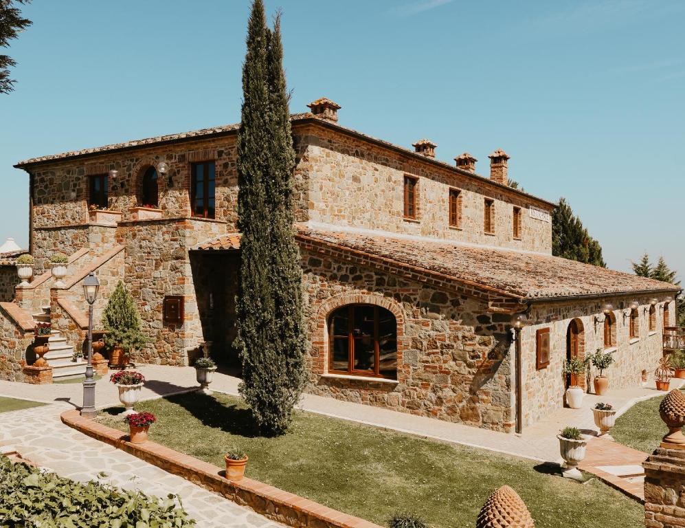 une vieille maison en pierre avec un arbre dans la cour dans l'établissement Poggio Paradiso Resort & Spa, à Montefollonico