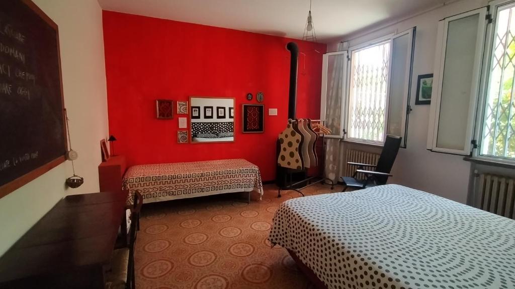 um quarto com duas camas e uma parede vermelha em la melagrana rossa em Quattro Castella