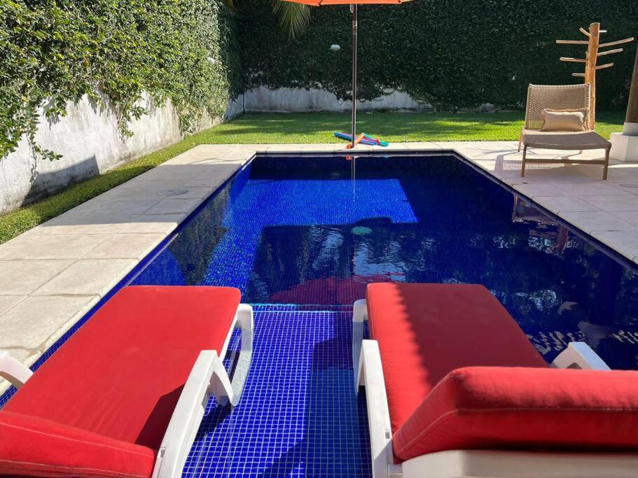 a swimming pool with two red chairs and an umbrella at CH036 Casa linda de playa in San José de Guatemala