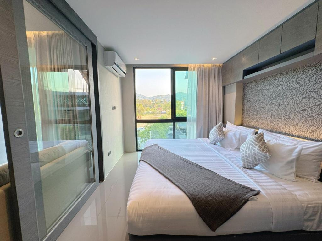 a bedroom with a large bed with a large window at Modern Urban Living Kamala in Kamala Beach