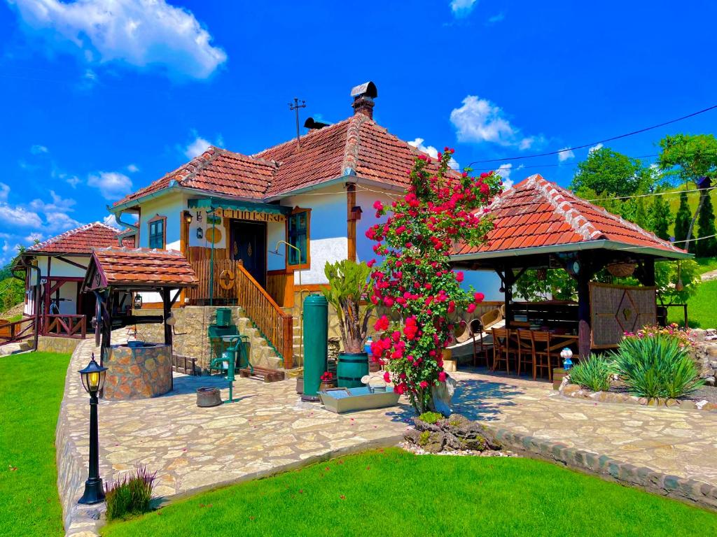 a small house with a gazebo and flowers at Etno selo Stanojevic in Boljevac
