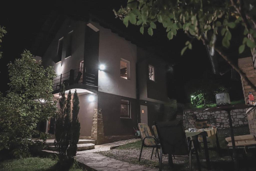 a house with a table and a balcony at night at Zeleni kutak in Sarajevo