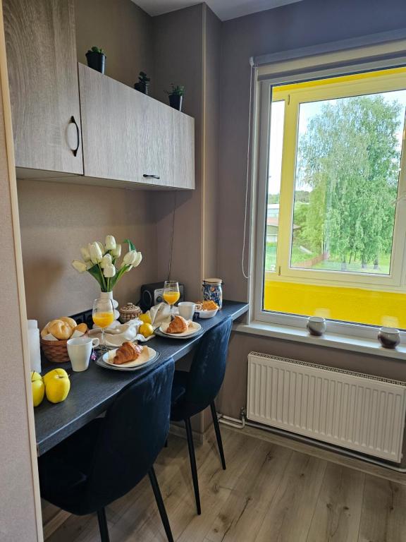 a table with plates of food and a window at JD apartment in Ozolnieki