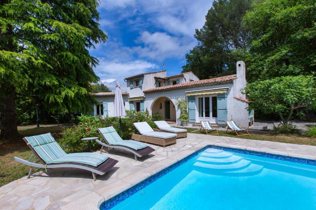 a swimming pool with chairs and a house at La Saliniere in Roquefort-les-Pins