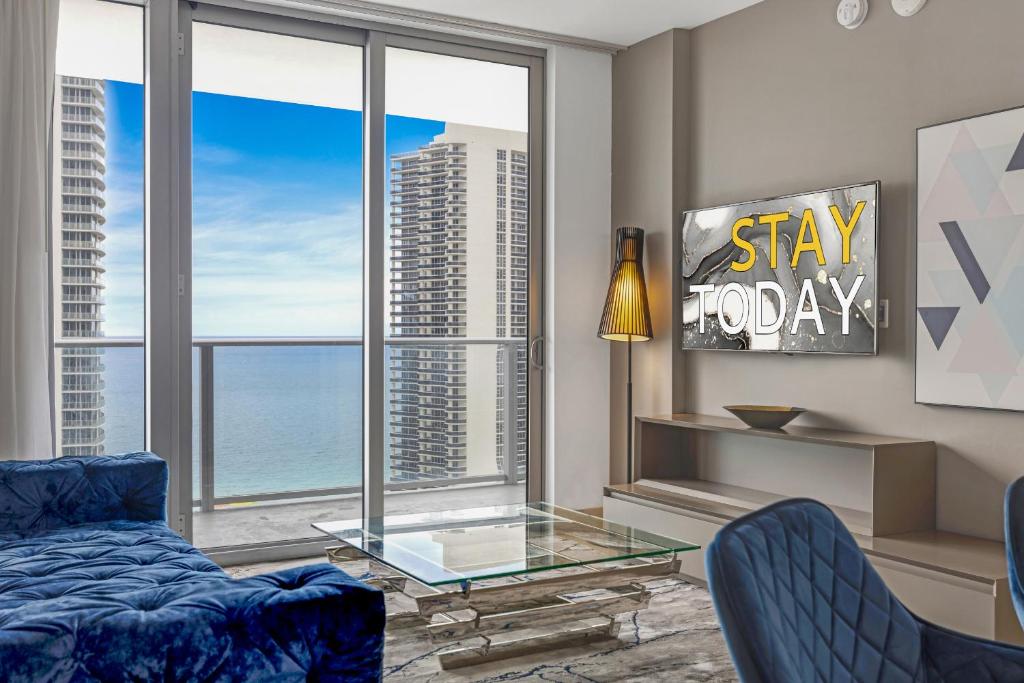 ein Wohnzimmer mit einem blauen Sofa und einem Glastisch in der Unterkunft HYDE HOUSE - Luxury Waterfront 2BR 2BA Apartment Suite with direct ocean view, roof top pool, resort amenities in Hollywood
