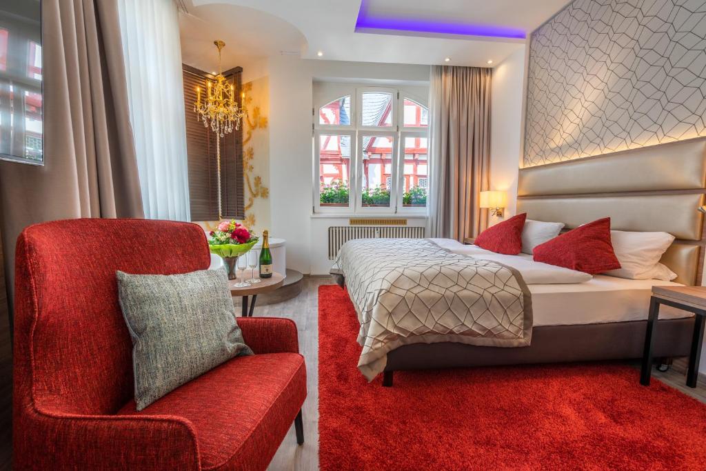 a bedroom with a bed and a red chair at Hotel am Markt Bacharach in Bacharach