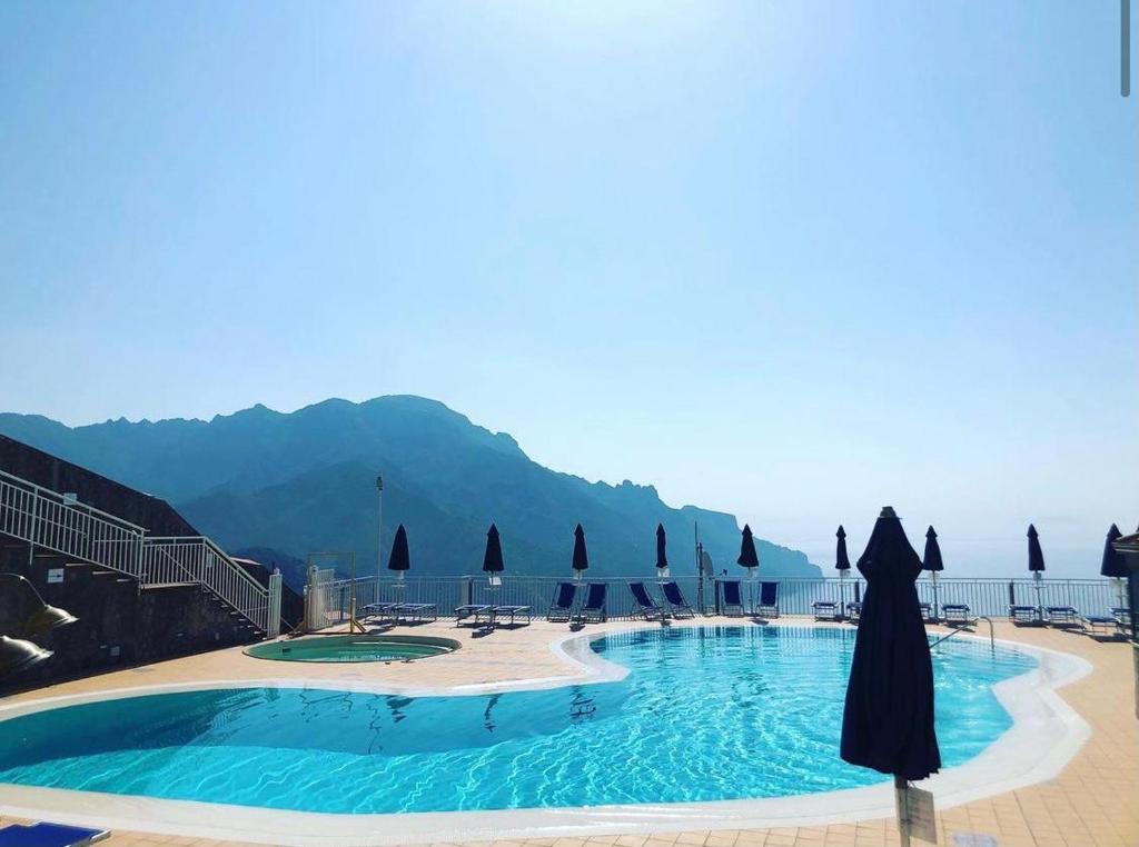 una grande piscina con ombrelloni e l'oceano di Casa Vacanza Ginevra a Ravello