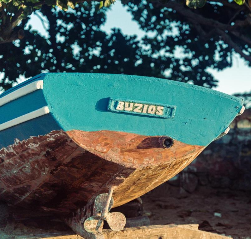 een houten boot met een bord aan de zijkant bij Peixe Crew Manguinhos in Búzios