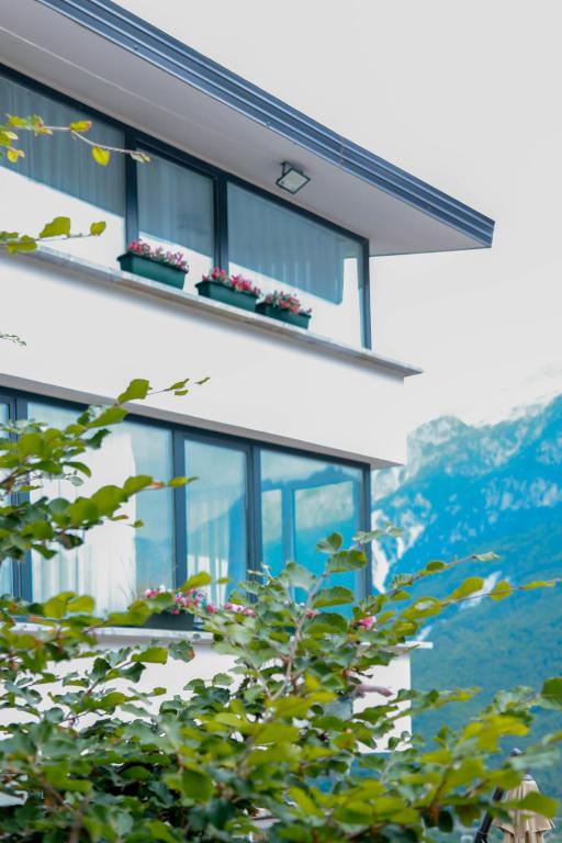 a building with windows with mountains in the background at Hotel Thethi in Theth