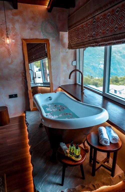 a bathroom with a large tub and a large window at Hotel Thethi in Theth