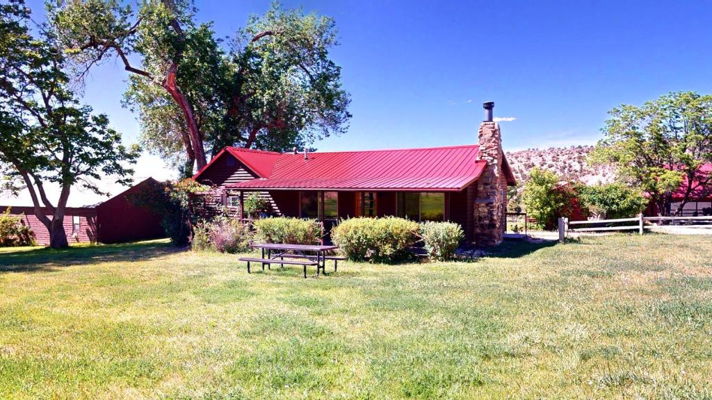 a house with a red roof and a bench in the grass at Pack Creek ~ Farm House in Moab