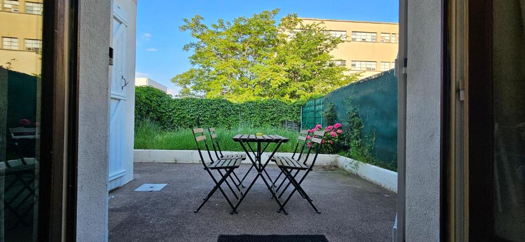 une table et deux chaises assises à l'extérieur d'une porte dans l'établissement Charmante Maison avec jardin sans vis-à-vis, à Saint-Fons