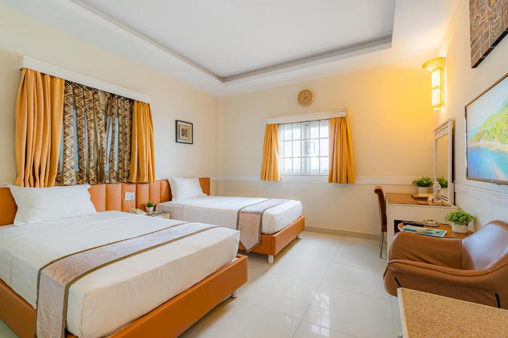 um quarto de hotel com duas camas e uma cadeira em Fortune 1127 - Central Hotel em Ho Chi Minh