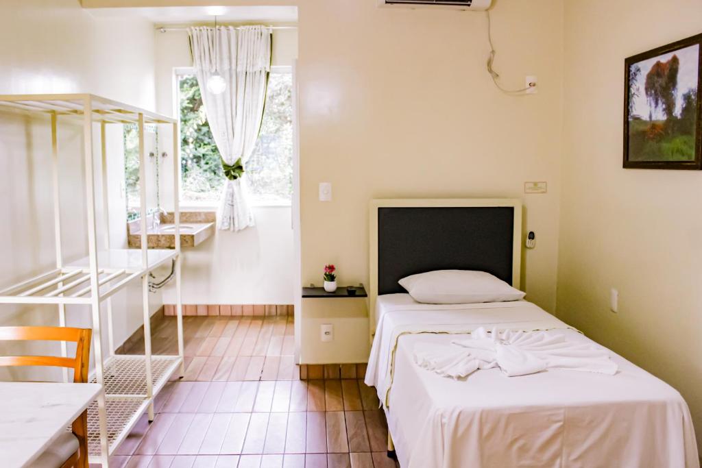 1 dormitorio con cama, mesa y ventana en Hotel Primavera Betim en Betim