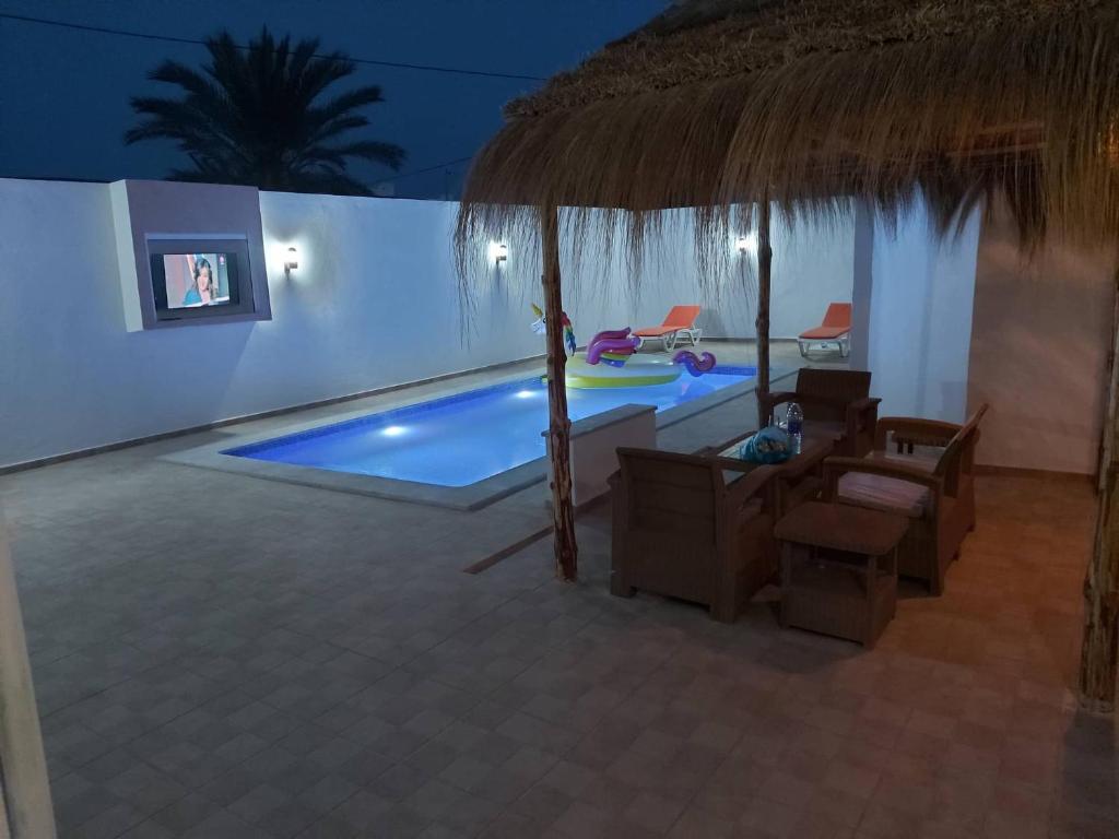 eine Villa mit einem Pool mit einem Strohschirm in der Unterkunft Villa TAGUERMES in Taguermess