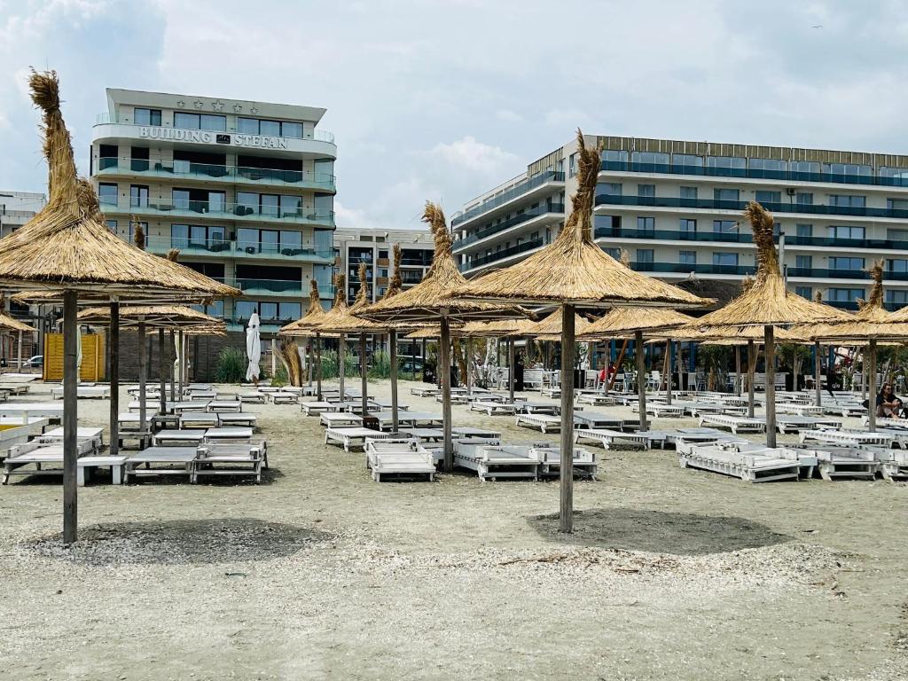- un groupe de chaises longues et de parasols sur une plage dans l'établissement GooApartments Three, à Mamaia Nord – Năvodari