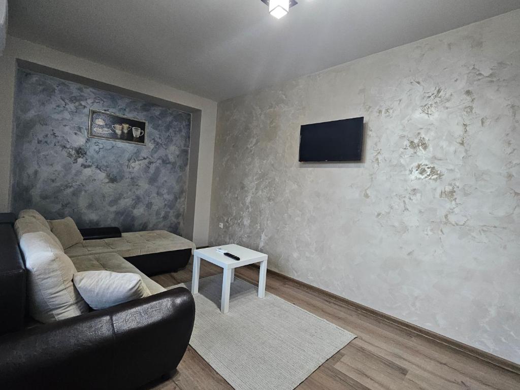 sala de estar con sofá y TV en la pared en Дунав билдингс, en Pleven