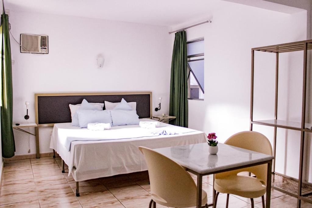a bedroom with a bed and a table and chairs at Hotel Primavera Betim in Betim