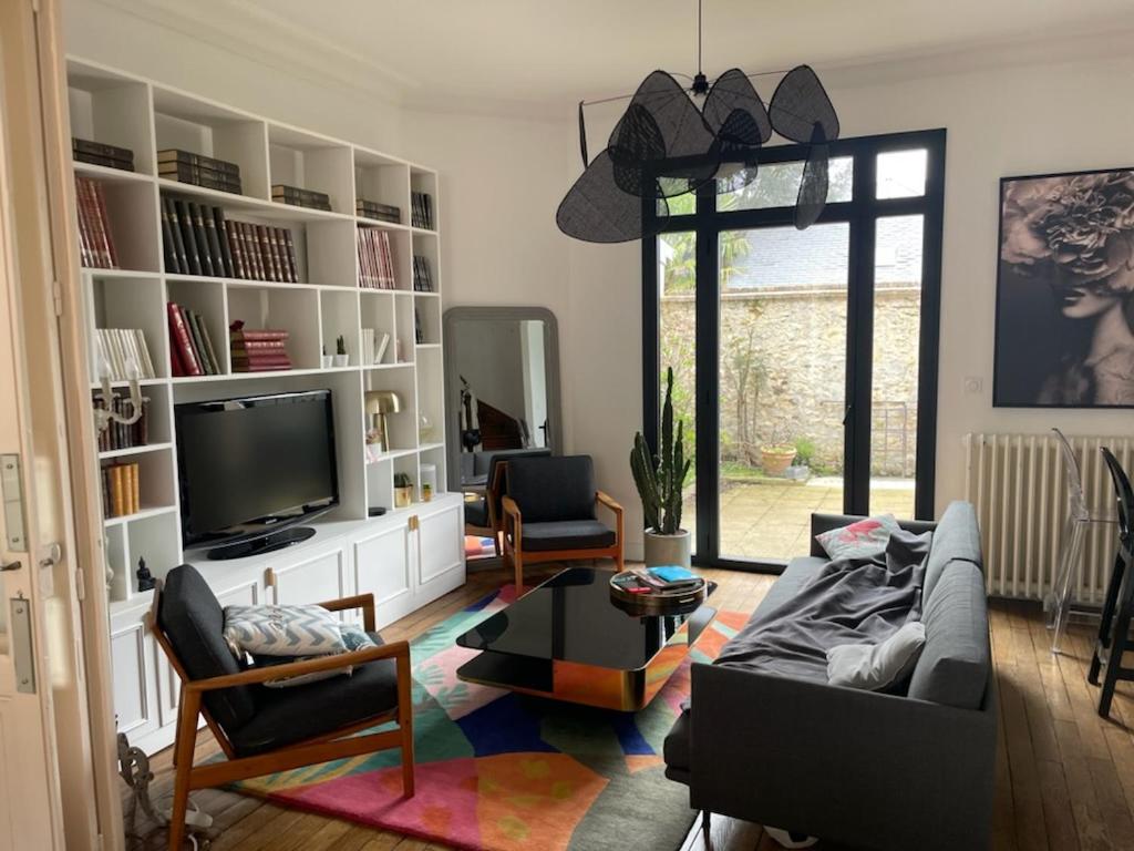 un salon avec un canapé et une télévision dans l'établissement Maison de caractère Le Mans 3 min à pieds gare et tram, proche centre ville, au Mans