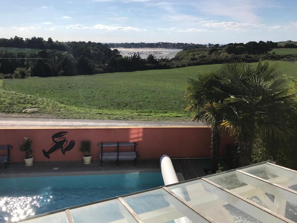 a swimming pool with a view of a field at Le Clos du Lupin in Saint-Coulomb