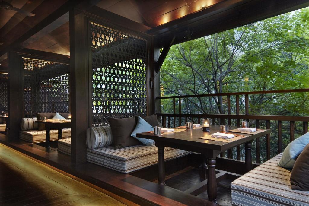 a screened in porch with a table and couches at Anantara Chiang Mai Resort in Chiang Mai