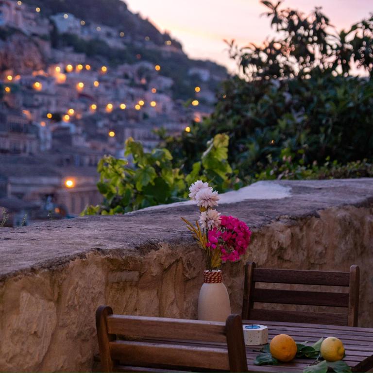 a table with a vase of flowers sitting on top of a stone wall at Villa Gelsomino in Modica