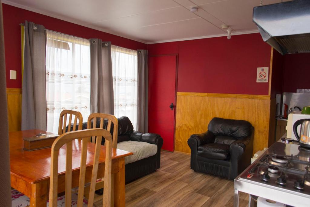 salon z czerwonymi ścianami oraz stołem i krzesłami w obiekcie Departamento Hikari w mieście Puerto Natales