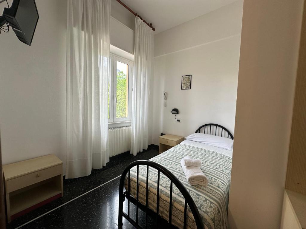 a bedroom with a bed with two chairs and a window at Hotel La Pineta in Cogoleto
