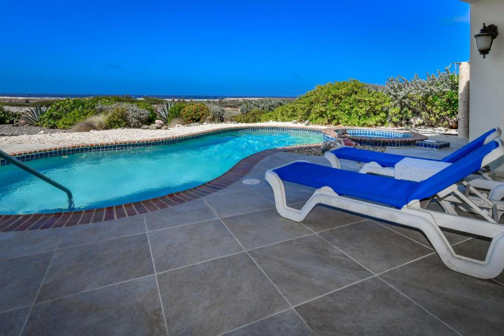 - une piscine avec 2 chaises longues et une télévision dans l'établissement Tierra Del Sol Resort & Golf, à Palm-Eagle Beach