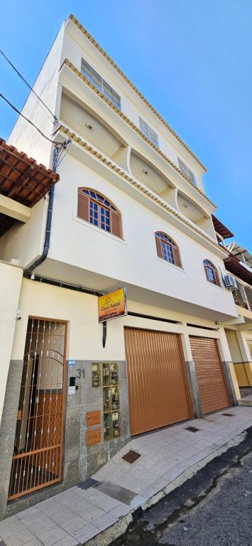 un bâtiment blanc avec des portes brunes dans une rue dans l'établissement CAXU HOSTEL, à Cachoeiro de Itapemirim