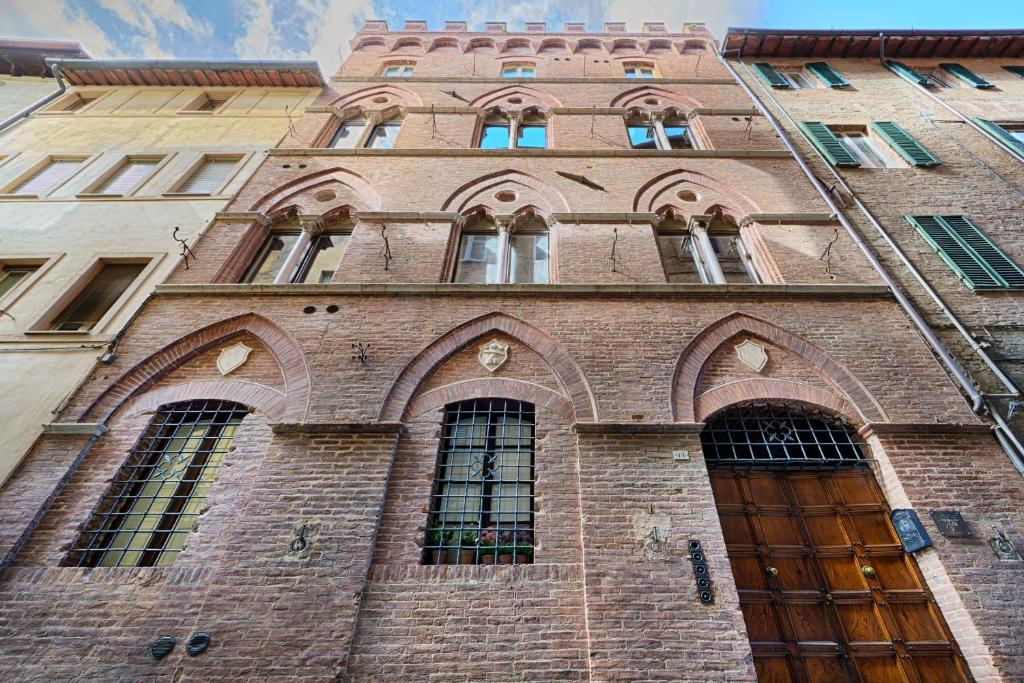 um edifício de tijolos alto com muitas janelas em I Merli di Ada em Siena