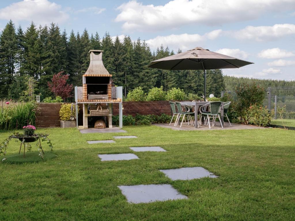 a backyard with an outdoor grill and an umbrella at Escapade en Ardenne - Appartement Sur Jardin Verdoyant in Bertrix