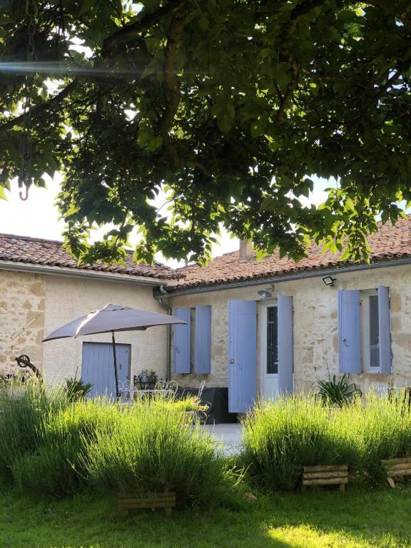 un bâtiment avec des portes bleues et un parapluie dans l'établissement Charmant Horse and Cottage Hideaway, à Doulezon