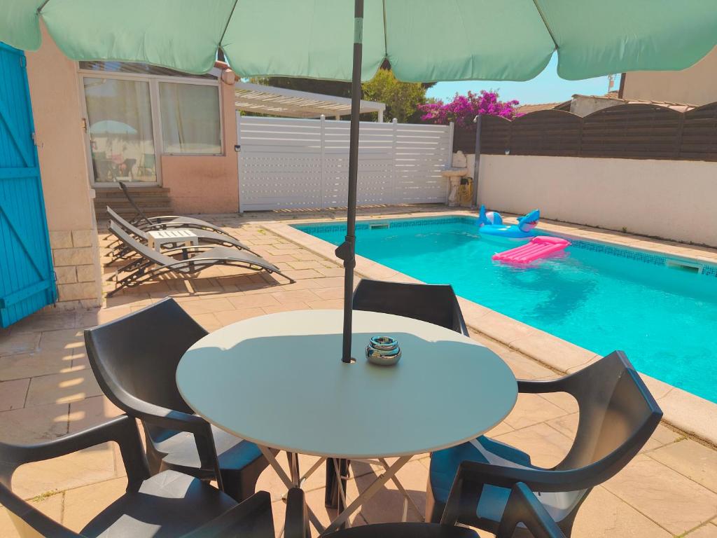 - une table et des chaises avec un parasol à côté de la piscine dans l'établissement Bel appartement avec piscine, à Martigues