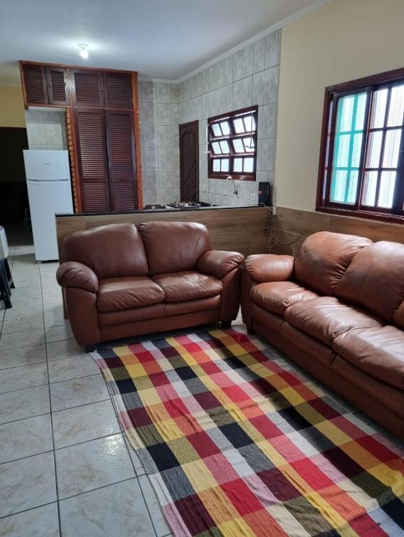 ein Wohnzimmer mit zwei braunen Ledersofas und einem Teppich in der Unterkunft Casa completa a 300 mts da praia in Itanhaém