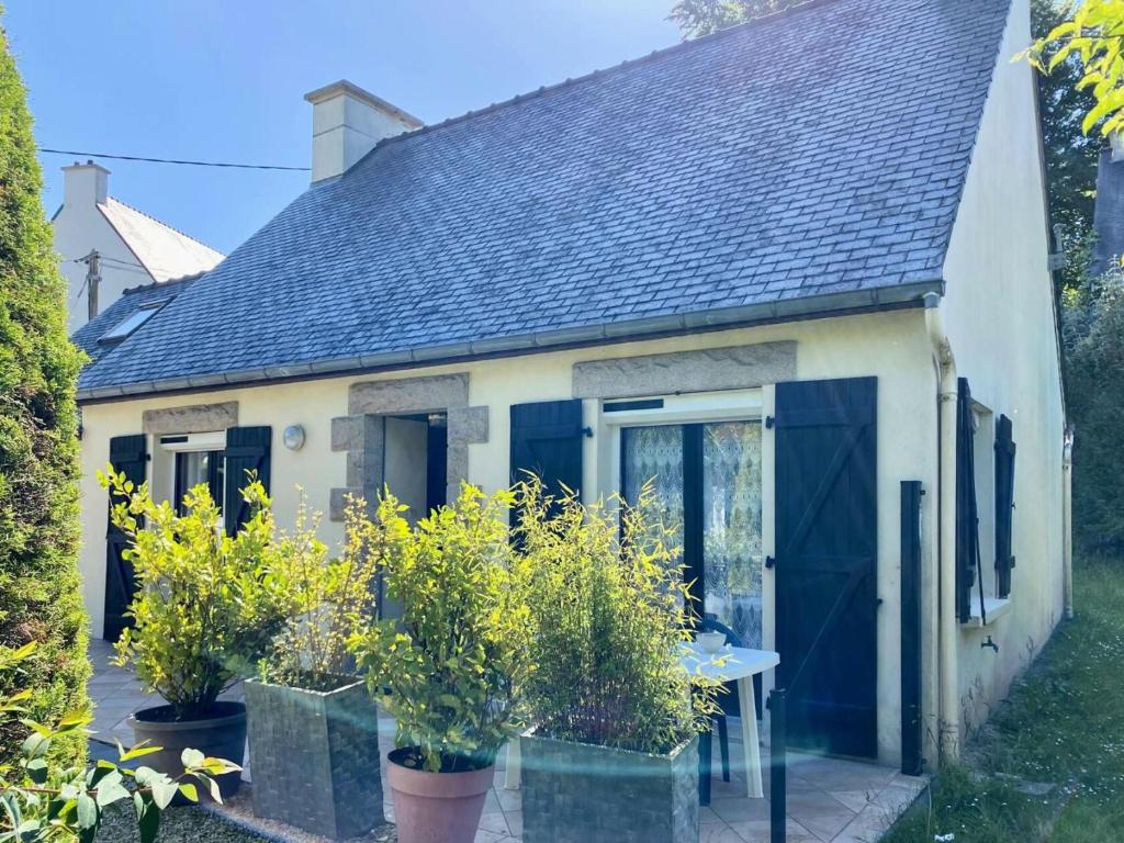 une petite maison avec des portes bleues et des plantes en pot dans l'établissement Résidence M100-perros Guirec - Maison avec jardin clos à Perros Guirec MAE-3524, à Perros-Guirec