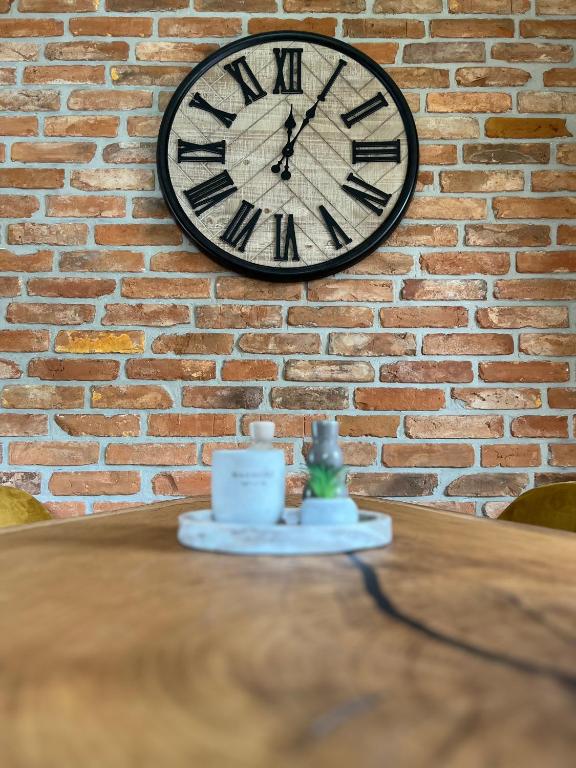 a clock on a brick wall next to a table at Haus Schönsee - 2 Apartments, ideal für Familien & Freunde in Heede