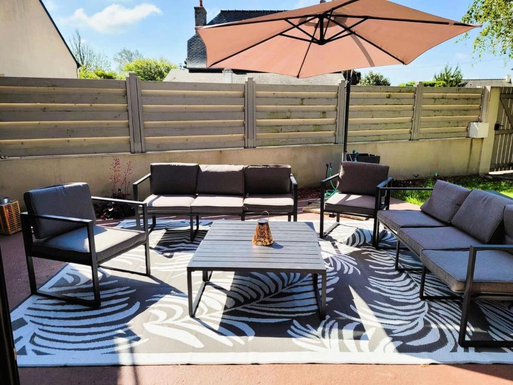 un patio avec une table, des chaises et un parasol dans l'établissement Résidence Ker Sanmamaleo - Villa Ker Sanmamaleo vacances près de la plage MAE-3604, à Pleumeur-Bodou