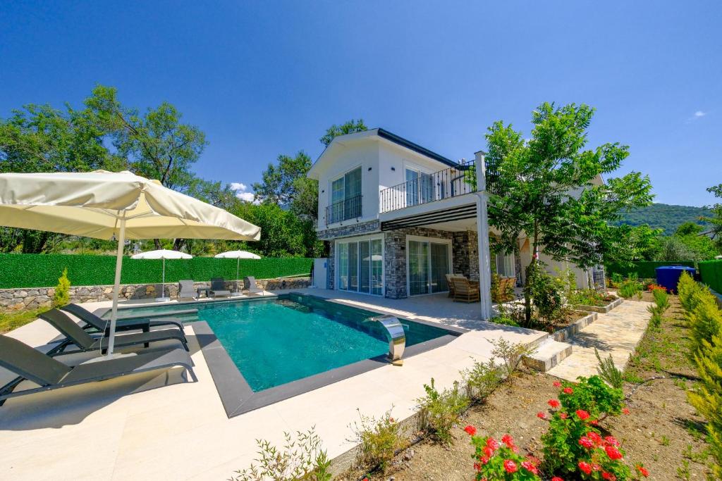 une maison avec une piscine et un parasol dans l'établissement Green Hills Luxury Villa Fethiye, Yesiluzumlu by Sunworld Villas, à Fethiye