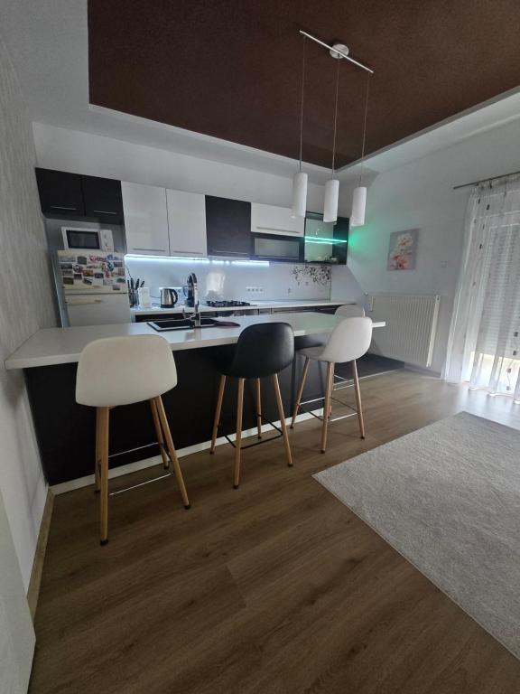 a kitchen with three chairs and a table and a counter at Apartman Nia in Bihać