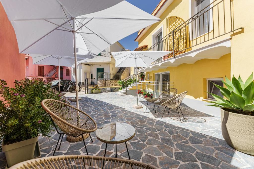 Un patio con sillas, mesas y sombrillas. en Ciraccio Apartments, en Procida