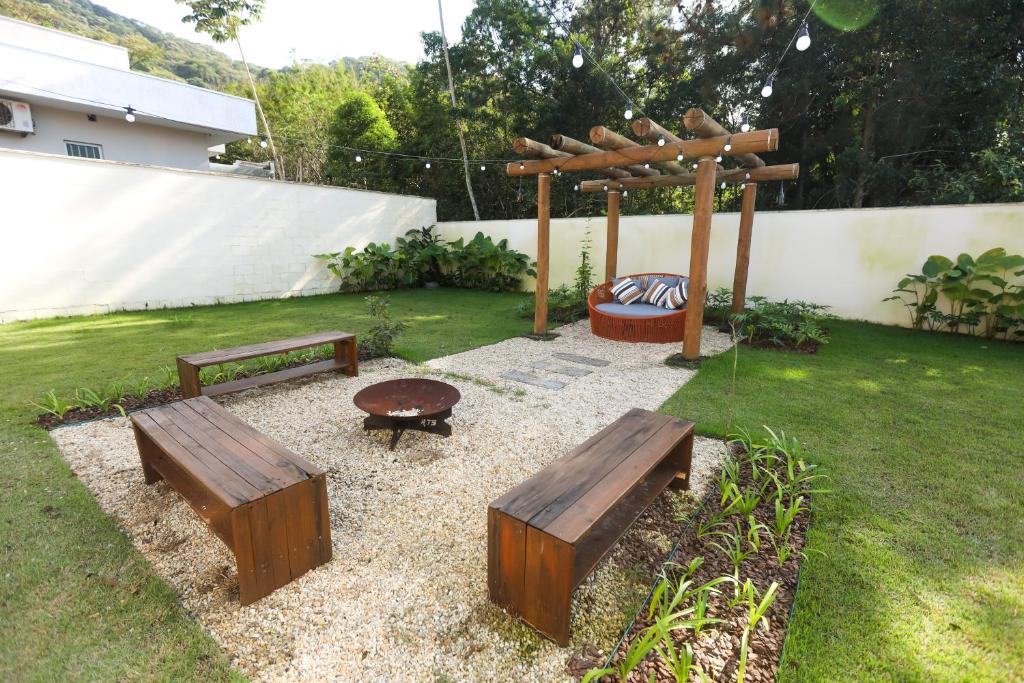 a garden with two benches and a wooden pergola at Lindo Sobrado em Balneário Camboriú in Balneário Camboriú