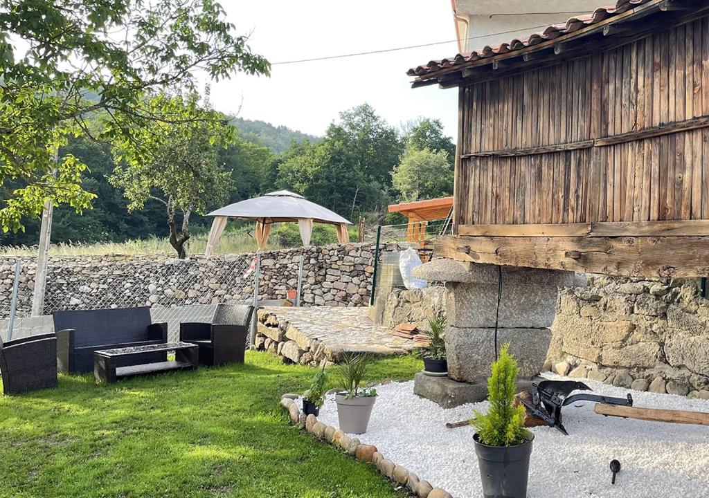 un jardín con una pared de piedra y una sombrilla en Casita del Río Ourense, en Ourense