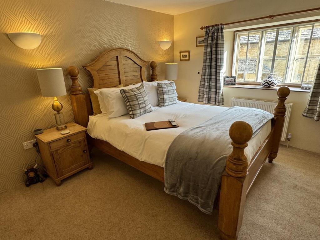 una camera da letto con un grande letto con un libro sopra di Guiting Guest House a Guiting Power