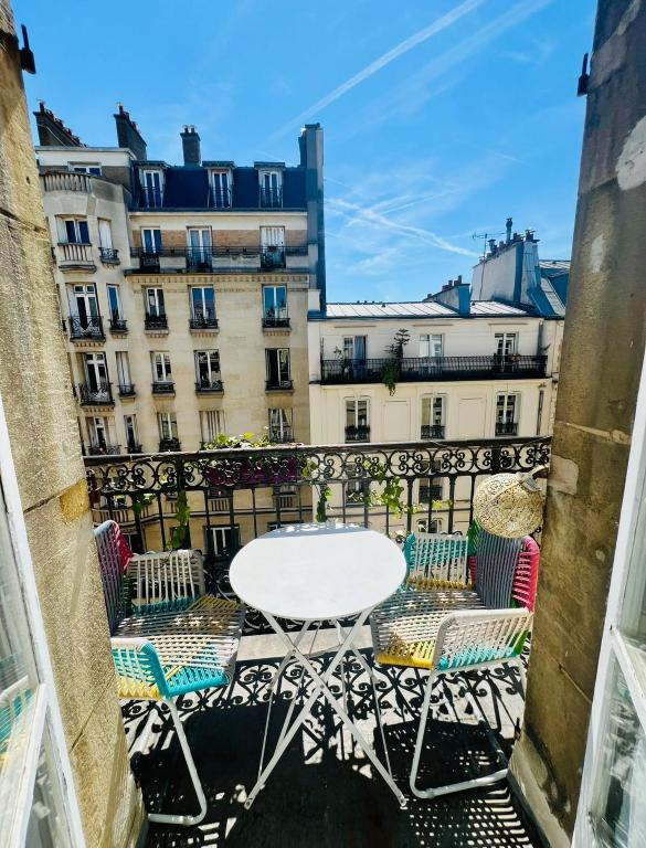 - une table et des chaises sur un balcon avec des bâtiments dans l'établissement Mon Cocon Parisien, à Paris