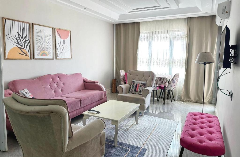 sala de estar con sofá rosado y sillas en Midyat Merkezde Lüks Daire en Midyat